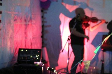 Dave playing his fiddle in the dark, in a tent