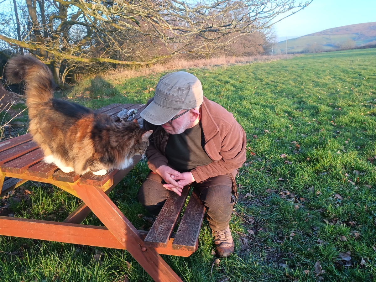 Dave greets Kizzy the cat in spring sunshine